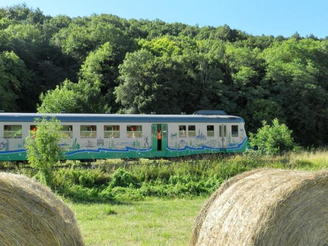 Train touristique avec en premier plan des bottes de paille à la campagne à Thoré-la-Rochette