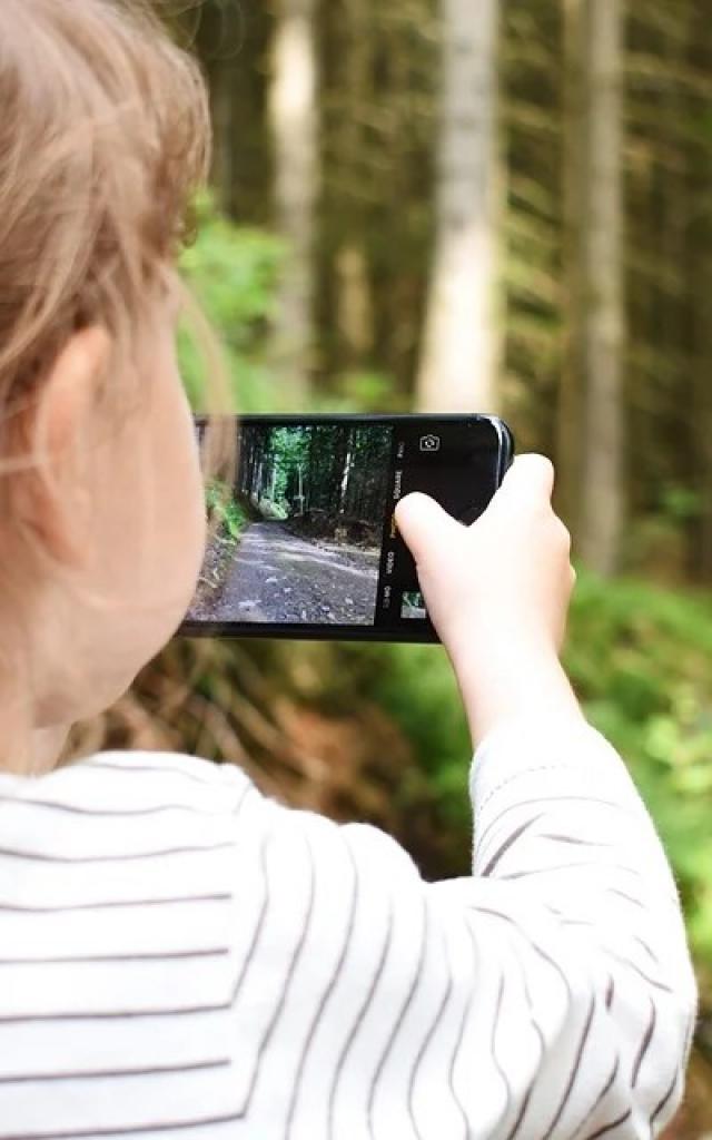 Une fillette avec un portable à la main dans la nature