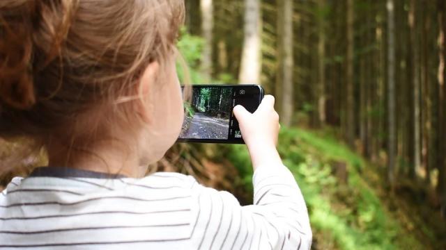 Une fillette avec un portable à la main dans la nature