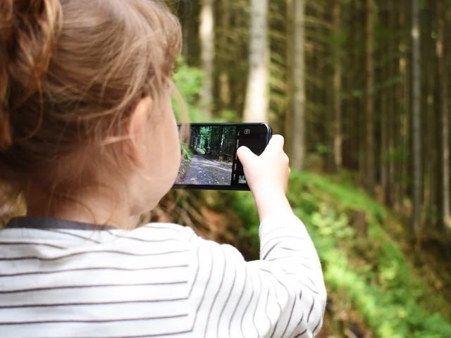 Une fillette avec un portable à la main dans la nature