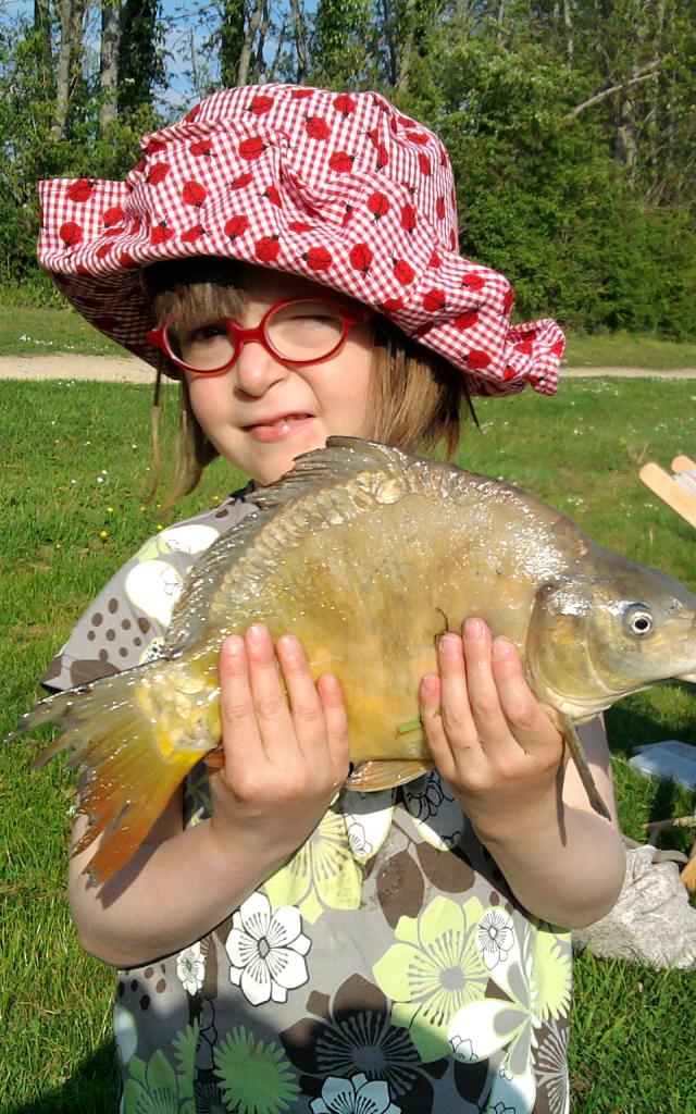 Une petite fille avec un gros poisson dans les mains