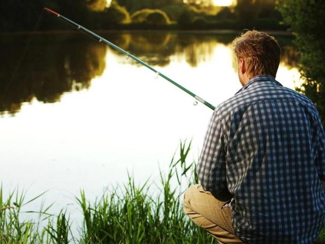 Un pécheur de dos pêche dans un étang