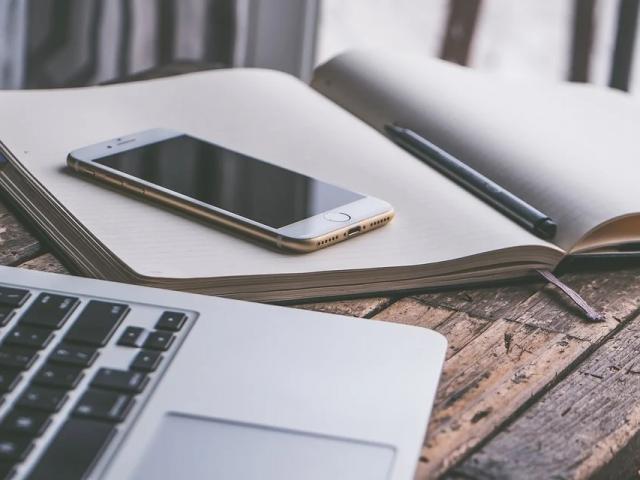 Un cahier, portable et ordinateur posé sur une table