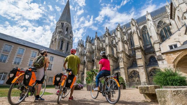 3 cyclistes en train de regarder une abbatiale