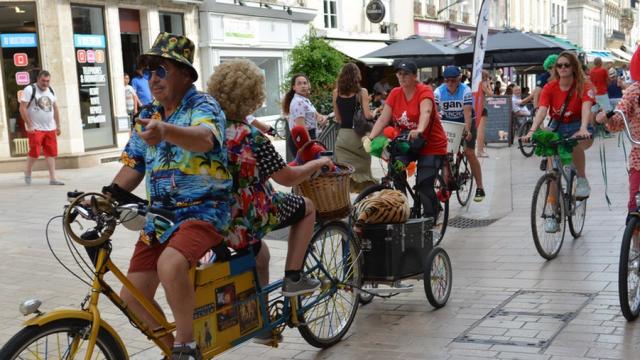 Personnes déguisées en train de faire du vélo dans une rue piétonne