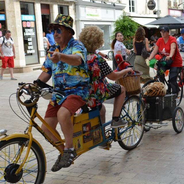 Personnes déguisées en train de faire du vélo dans une rue piétonne