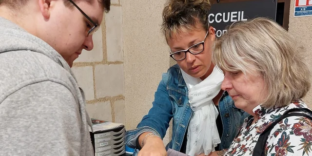 Accueil de l'Office de Tourisme avec une conseillère et deux touristes