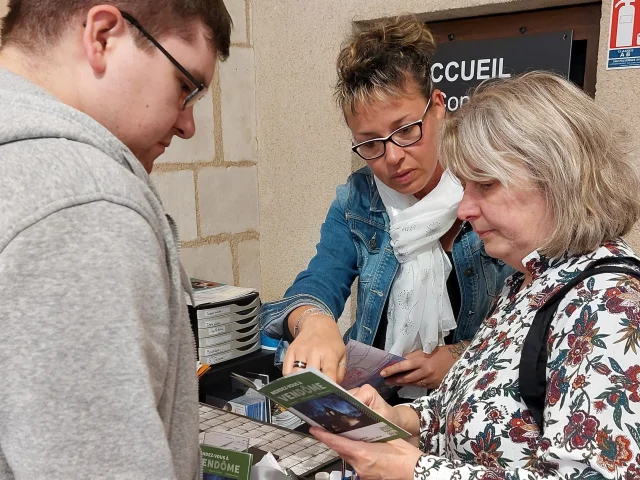 Accueil de l'Office de Tourisme avec une conseillère et deux touristes