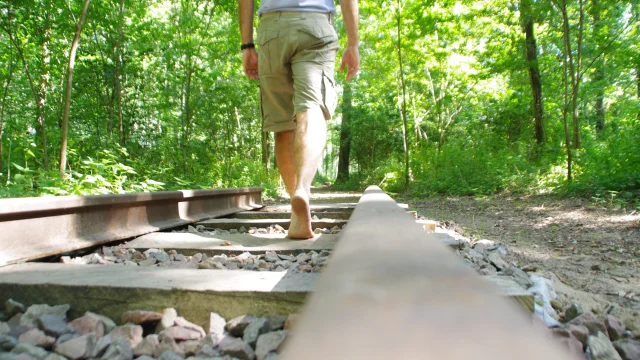 Une personne de dos (on ne vois que du bassin au pied) sir un sentier pied nu dans la nature