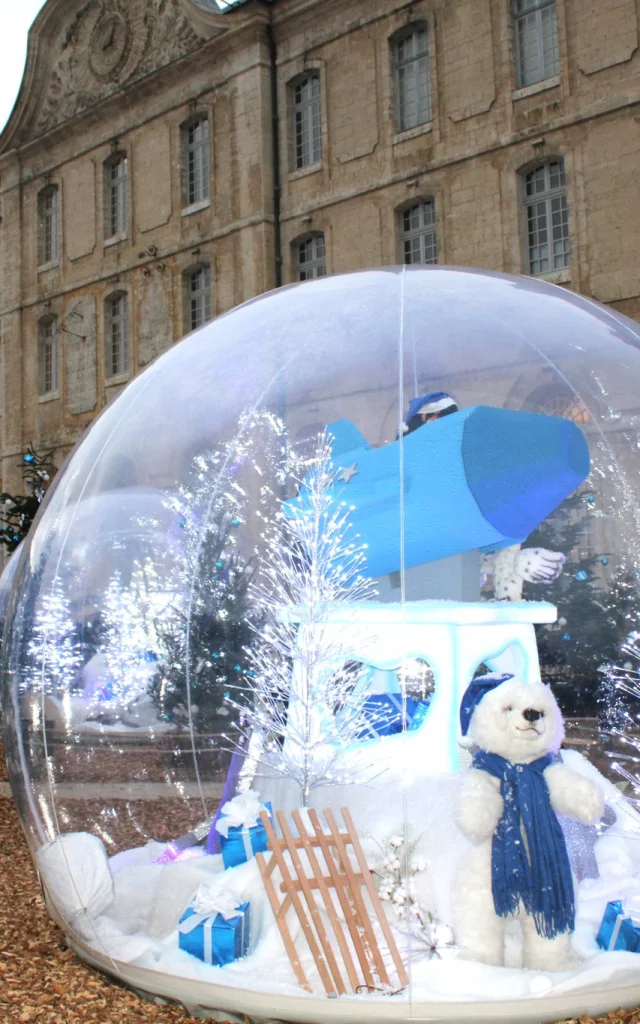 Boule de Noël avec nounours à l'intérieur devant un bâtiment historique