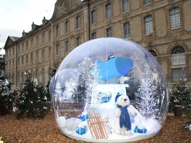 Boule de Noël avec nounours à l'intérieur devant un bâtiment historique