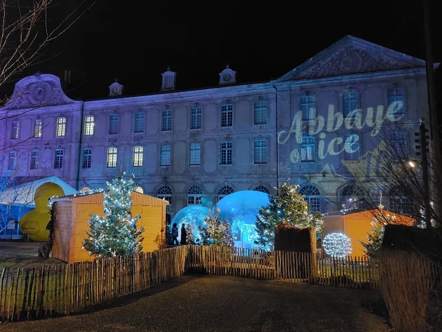 Façade d'un bâtiment éclairé de nuit avec bulles de Noël et chalet