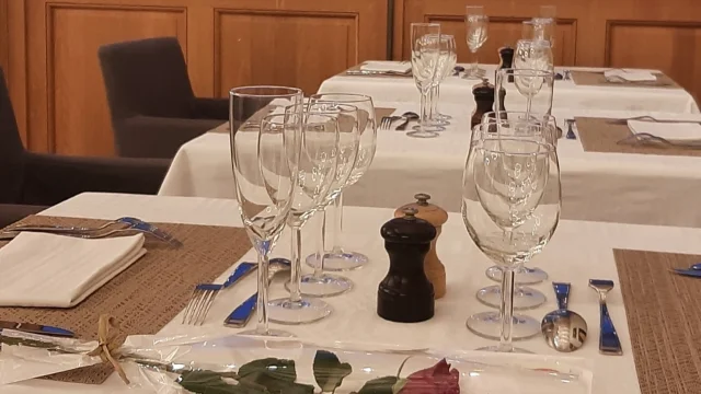 Table dressée dans un restaurant avec couverts, verres et une rose posée au premier plan