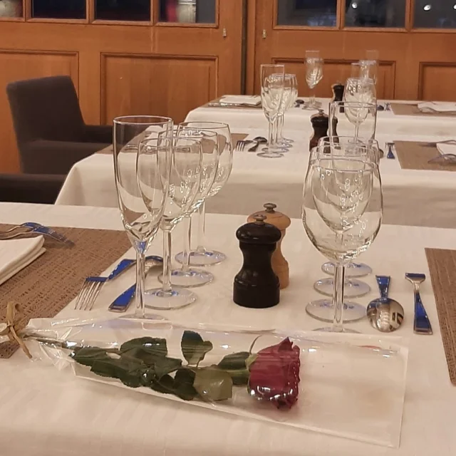 Table dressée dans un restaurant avec couverts, verres et une rose posée au premier plan