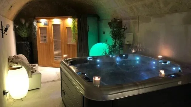 Cave avec à l'intérieur spa au premier plan, sauna au deuxième plan et lampe blanche à gauche