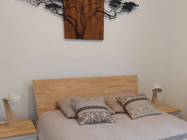 Chambre avec lit draps beiges marron avec arbre sur le mur